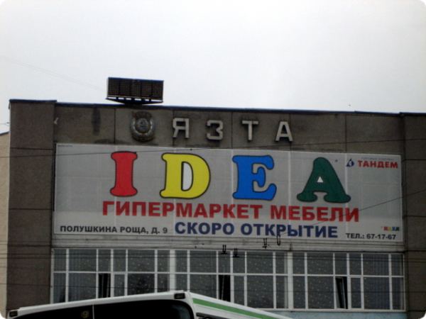 На фасаде здания вывеска «IDEA ГИПЕРМАРКЕТ МЕБЕЛИ» с надписью «СКОРО ОТКРЫТИЕ», адрес: Полушкина роща, д. 9, телефон: 67-17-67, логотип «ТАНДЕМ».