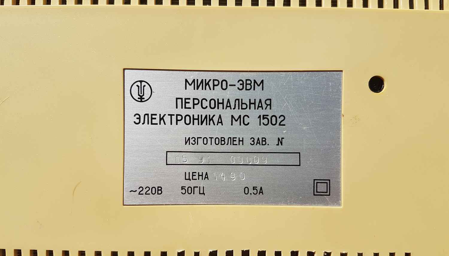 Металлическая табличка на бежевом корпусе: «МИКРО-ЭВМ ПЕРСОНАЛЬНАЯ ЭЛЕКТРОНИКА МС 1502», заводской № 05 91 00009, цена 1490, ~220В 50Гц 0,5А, знак качества и квадратный символ.