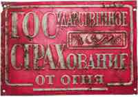 Ржавая красная табличка с надписью «ГОСУДАРСТВЕННОЕ СТРАХОВАНИЕ ОТ ОГНЯ» — исторический знак страхового учреждения.