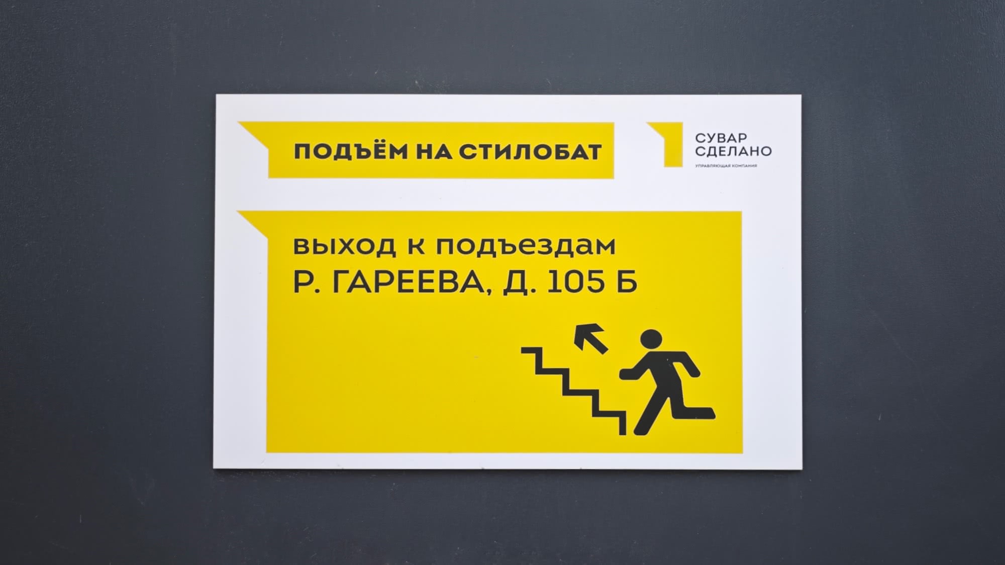 Навигационный знак: «ПОДЪЁМ НА СТИЛОБАТ», «ВЫХОД К ПОДЪЕЗДАМ Р. ГАРЕЕВА, Д. 105 Б» с иконкой лестницы и человека, логотип «СУВАР СДЕЛАНО».