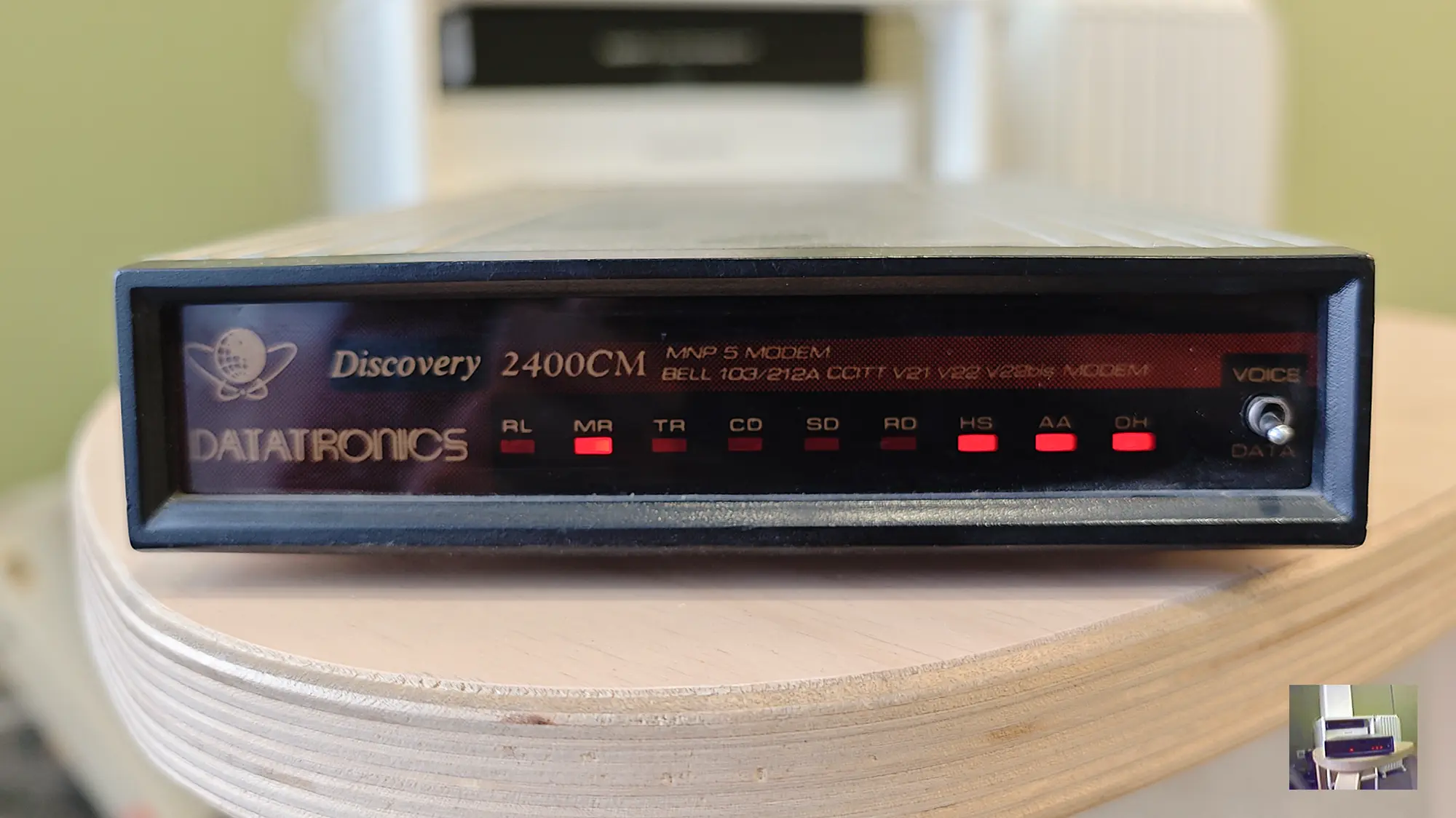 Модем Datatronics Discovery 2400CM с надписями MNP 5 MODEM, BELL 103/212A CCITT V21 V22 V23bis MODEM и переключателем VOICE/DATA; горят индикаторы MR, HS, AA, OH.