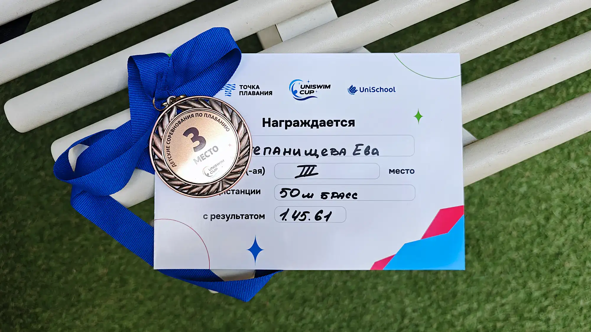 Награждение Евы Степанищевой за 3 место в плавании на 50 м брассом с результатом 1.45.61 на UNISWIM CUP, логотипы «Точка плавания» и UniSchool.