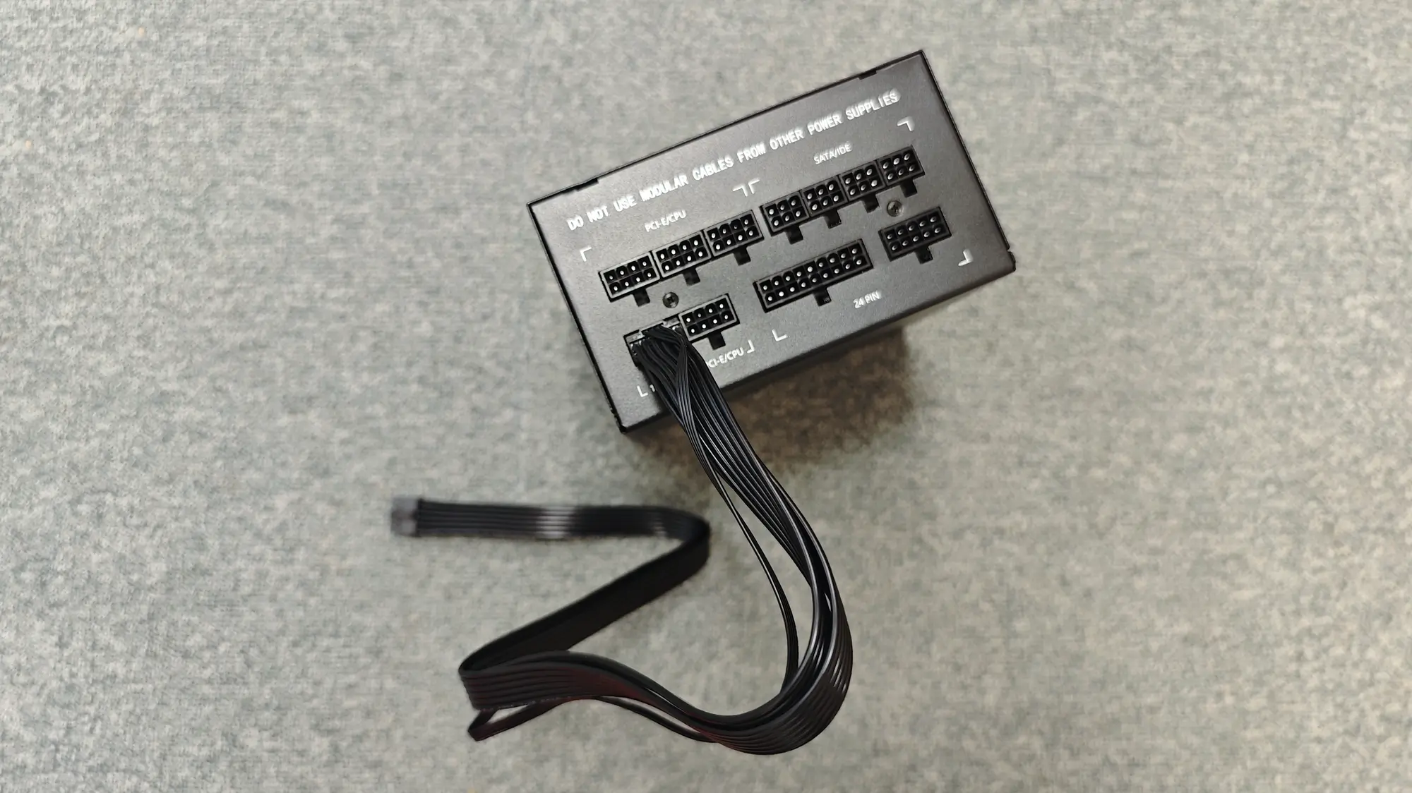 Блок питания с модульными кабелями, на корпусе надпись «DO NOT USE MODULAR CABLES FROM OTHER POWER SUPPLIES», видны разъёмы PCIe/CPU, SATA/IDE и 24-pin.