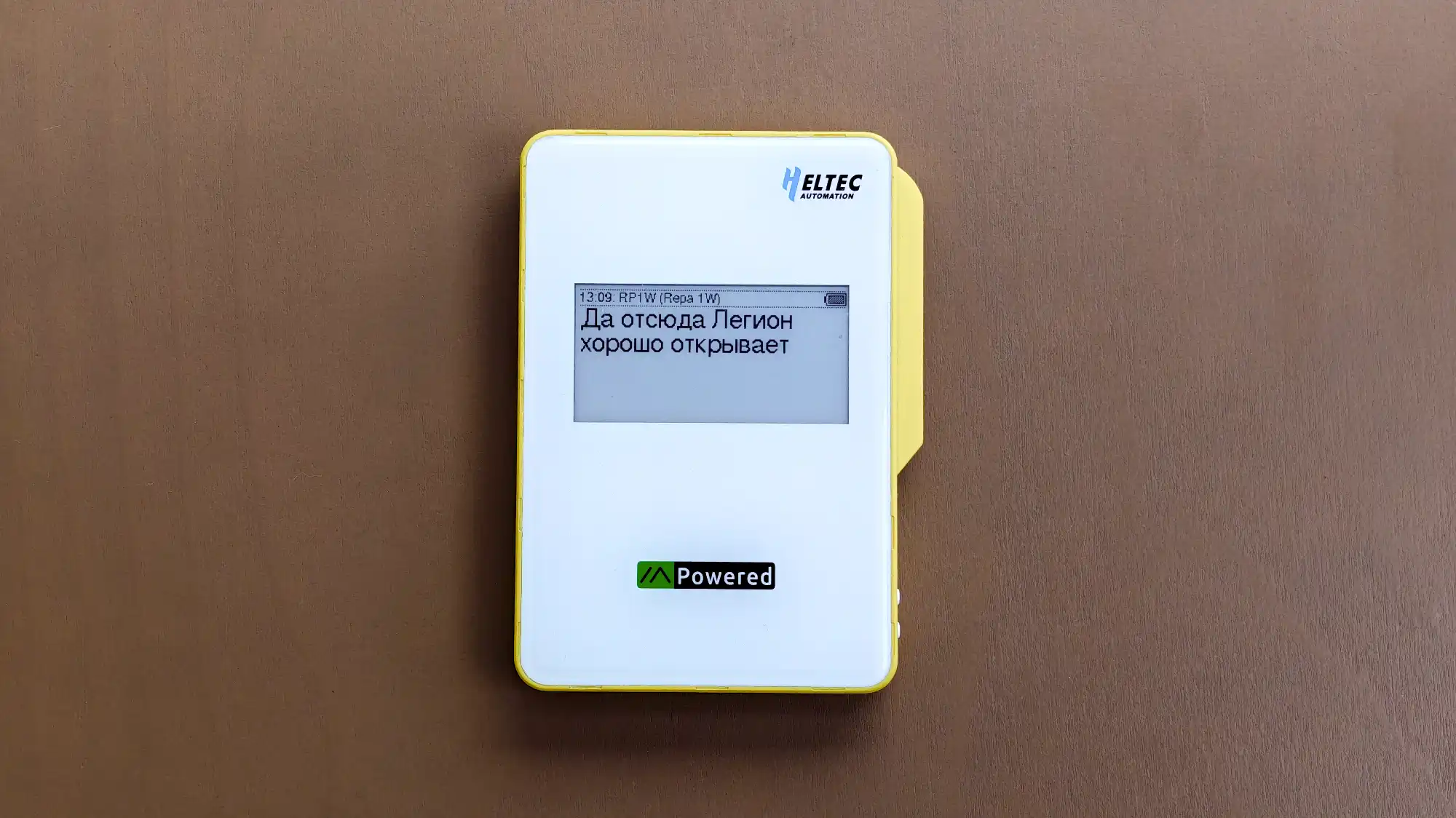 Устройство HELTEC Automation с экраном, на котором отображается текст: «13:09: RP1W (Repa 1W) Да отсюда Легион хорошо открывает» и надпись «Powered» внизу.
