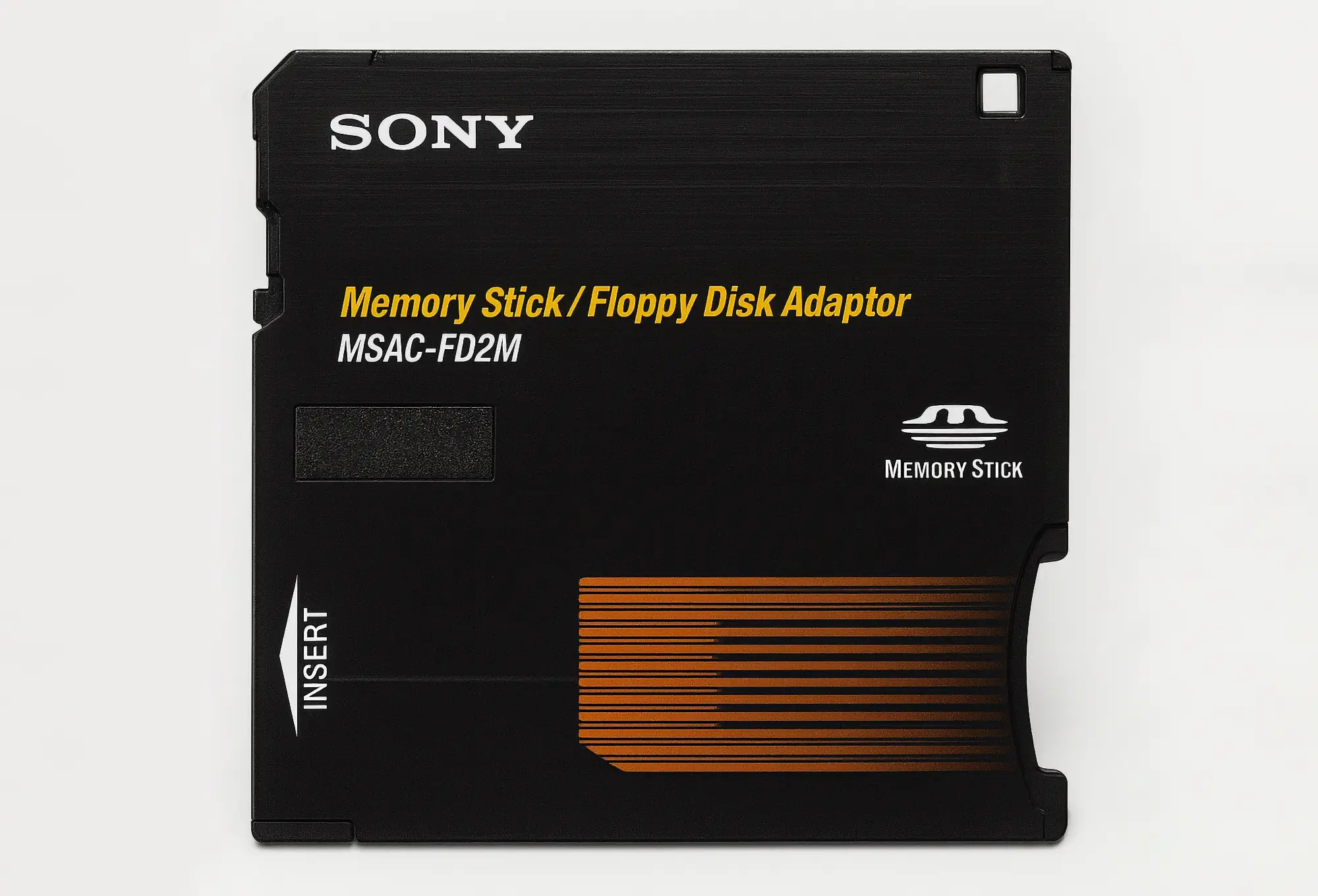 Адаптер Sony Memory Stick/Floppy Disk Adaptor MSAC-FD2M: чёрный корпус с жёлтой надписью, логотипом Memory Stick и оранжевыми полосами, маркировка INSERT.