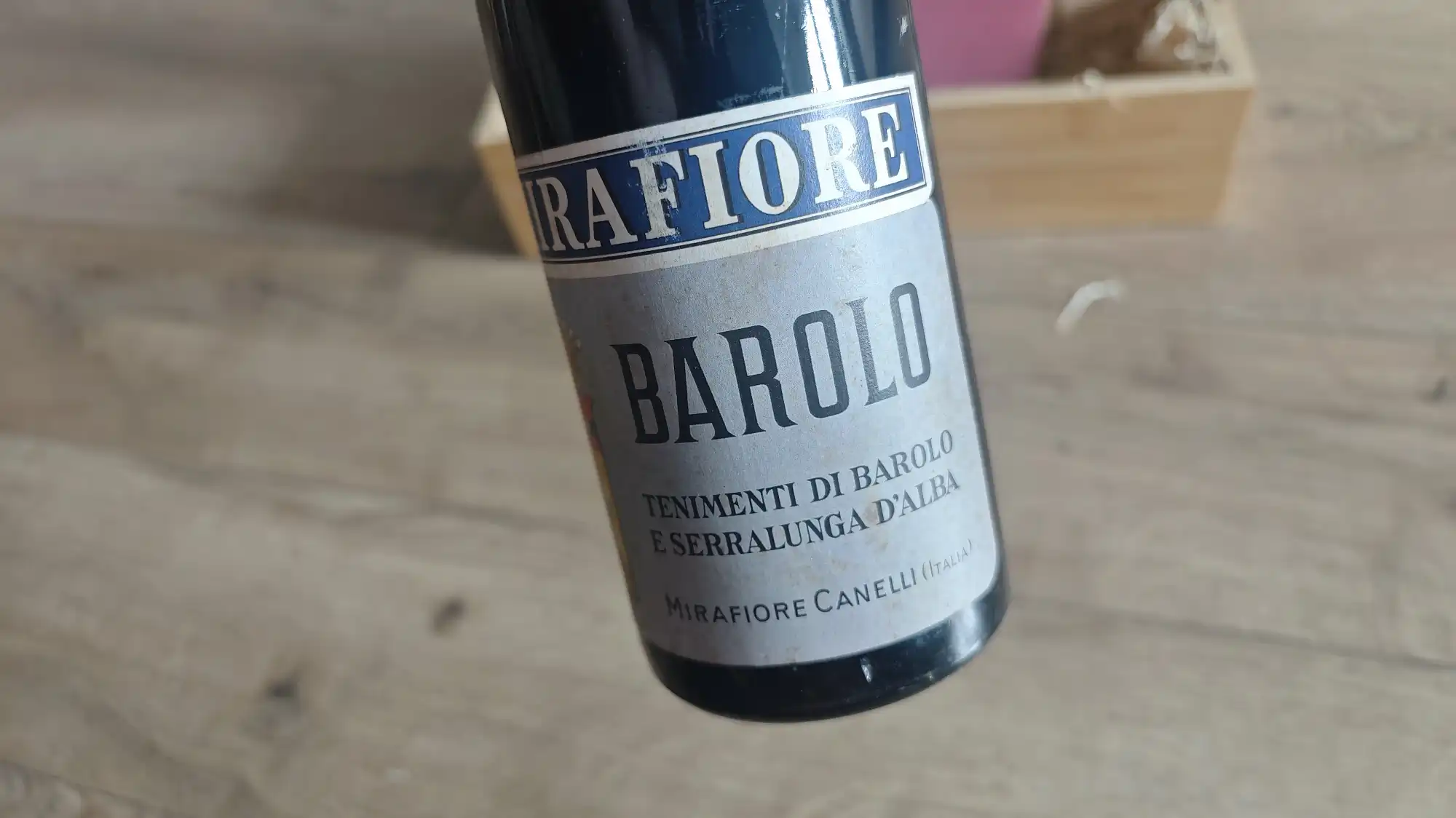 Бутылка вина Mirafiore Barolo с этикеткой «Tenimenti di Barolo e Serralunga d’Alba», производитель Mirafiore Canelli (Италия), на деревянном фоне.